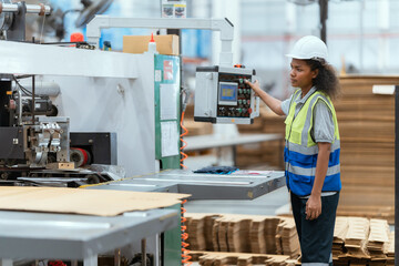 Machine operators work in a large paper factory and check stock of cardboard boxes.