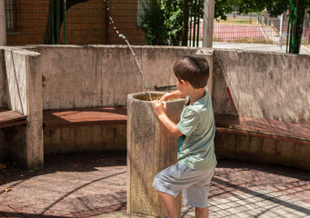 Child playing at fountain in a public park at city.