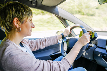 Female driver attentively navigates car on sunny rural road.
