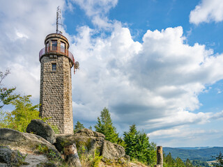The stone lookout tower of Prosecsky Hreben stands on rocky terrain against a partly cloudy sky,...