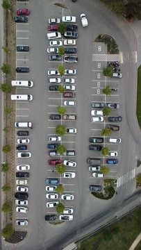 Busy large modern carpark with symmetrical roads rows of parking bays lots of symmetry and colours aerial view from drone up above looking down.