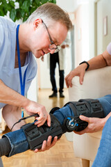 A male nurse helps to put a bondage, medical splint, knee brace on the leg of an elderly female patient who communicates with the attending physician at the clinic or hospital.