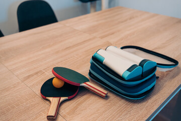 pingpong paddles, ball and net kit to play anywhere on an indoor table at home. Portable mini pingpong set open to be installed on a wooden table at home.
