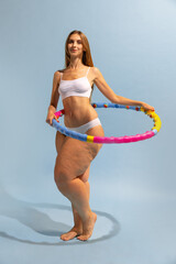 Motivation to be beautiful and healthy. Young slim girl with plus-size woman's body doing exercises with hoop. Conceptual design. Concept of weight-loss, sport and healthy eating, active lifestyle