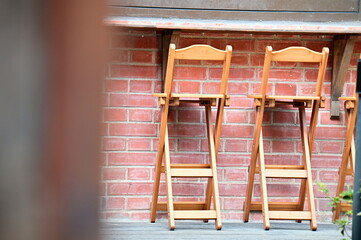 Clear day, outdoor red brick walls, bask in sunlight, accompanied by a few folding bar stools.