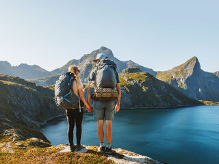 Couple backpackers hiking in mountains friends exploring Norway together active healthy lifestyle outdoor family summer vacations adventure trip, man and woman enjoying lake view in Lofoten islands