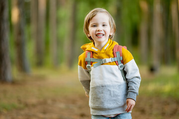 Cute little boy with a backpack having fun outdoors on sunny summer day. Child exploring nature. Kid going on a trip.