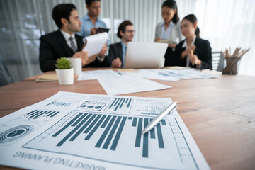 Piles of analyzed financial data dashboard on meeting table with background of business people...