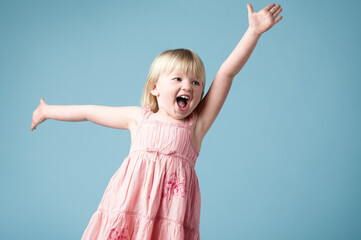 Studio, child or girl excited with dance for surprise, happy or isolated on blue background. Model, backdrop or kid for announcement with face reaction of wow, omg or shocked emoji with mind blown - obrazy, fototapety, plakaty