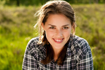 Woman, portrait and smile in grass field for spring with happiness, flowers and wellness. Female...