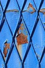 Detail of an old rusty diamond shaped fence painted in blue