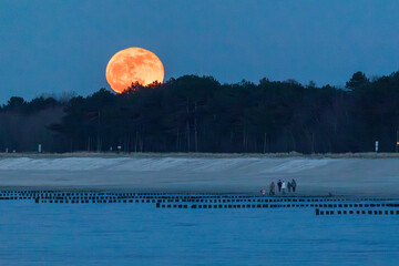 Augehender Vollmond über dem Strand von Zingst an der Ostsee.