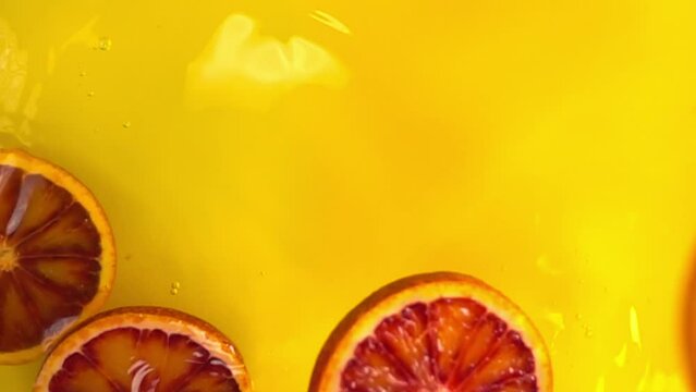 close up of natural red orange slices falling in juice, advertising of tropical fruit juice splashing, super slow motion