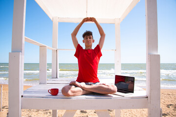 A young attractive man meditates by the sea.
