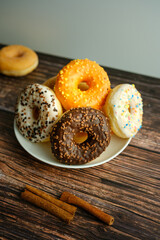 Color glazed donuts on a white plate wooden background. Desert Snack.