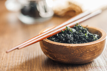Dried wakame seaweed in bowl on wooden table.
