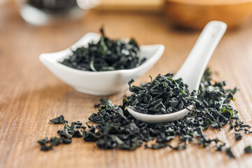 Dried wakame seaweed in spoon on wooden table. - 794992342