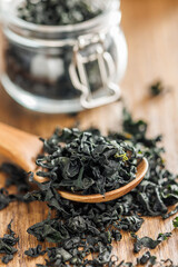 Dried wakame seaweed in spoon on wooden table. - 794992521