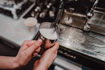 Skilled barista steaming milk for a cappuccino using a coffee machine, showcasing the art and precision of coffee making