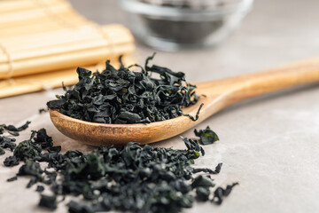 Dried wakame seaweed in spoon on kitchen table. - 794992956
