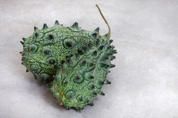 African cucumber, Kiwana fruit or horned melon on mottled grey with copy space