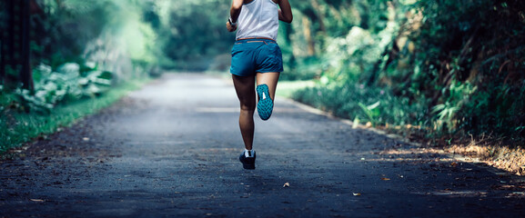 Fitness sportswoman runner running on tropical forest trail