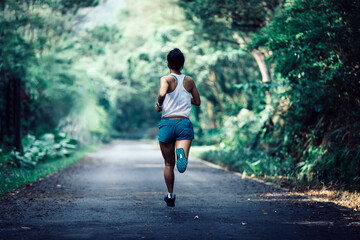 Fitness sportswoman runner running on tropical forest trail - obrazy, fototapety, plakaty