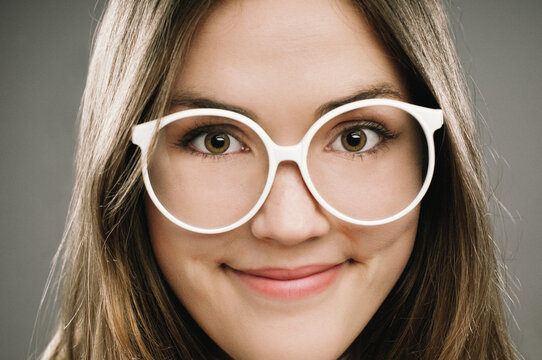 Glasses, portrait and smile with girl nerd in studio on gray background for accessories or fashion. Face, intelligence and vision with cute, happy geek closeup in eyewear for retro or vintage style