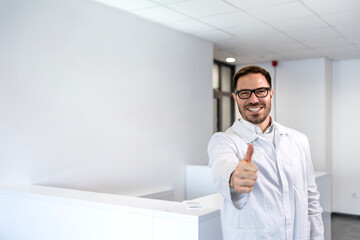 Handsome caucasian man in anti-static suit holding thumbs up in factory.