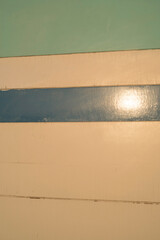Reflejo del sol en pared de tablones blancos y azules en caseta de playa