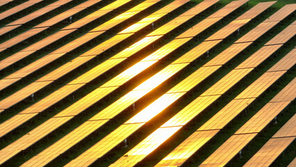 The solar photovoltaic farm mirrors the setting sun's golden splendor, a symbol of sustainable love between nature and technology. Eco-friendly fuels and Energy conservation concept. Aerial view.
