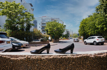 A pair of black women's shoes on a fence, against the background of the street.