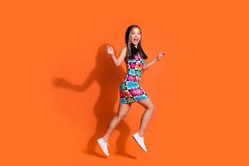 Full length photo of funky optimistic cute girl dressed print clothes run to empty space on sale isolated on orange color background