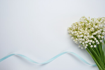Beautiful bouquet of fresh lily of the valley flowers with blue ribbon on a white background....