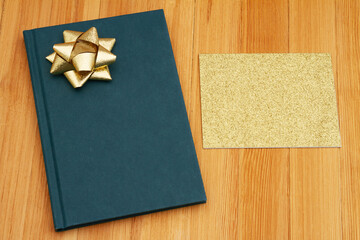 Retro old blue book with a gift bow and greeting card on a desk