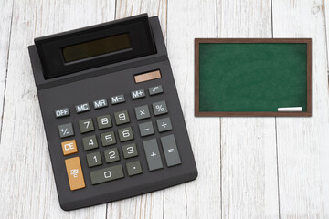 The cost of tuition for education with a black calculator with a chalkboard on wood desk