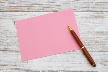 Blank pink greeting card with pen on wood