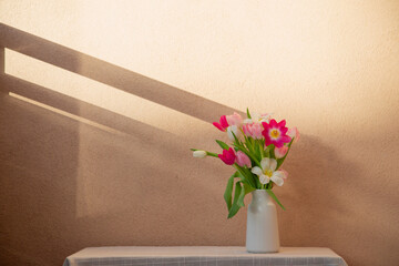 tulips in vase on table on background wall
