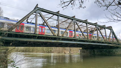 A train is crossing a bridge over the water under a cloudy sky Hanover Germany
