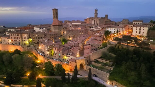 Aerial evening shot of Volterra town in Tuscany region of Italy. Volterra - medieval Tuscan town with old houses, towers and churches, with city lights after sunset