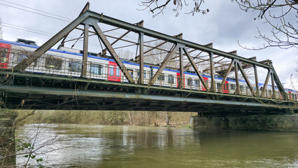 Fototapeta na wymiar A train crosses a bridge over water, under a cloudy sky Hanover Germany