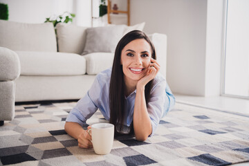 Full body portrait of lovely lady lay floor drink coffee wear blue shirt bright interior apartment indoors - obrazy, fototapety, plakaty