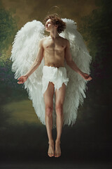 Divine Serenity. Handsome angelic figure with curls and white wings posing radiates sense of peace...