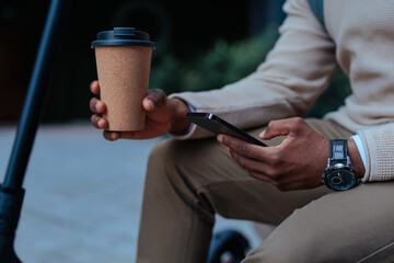 Man holding phone and coffee outdoors