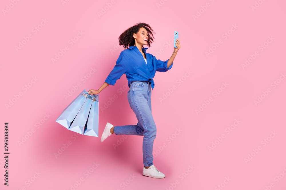 Poster Photo of charming cheerful girl stylish blue clothes go walk video call empty space isolated on pink color background