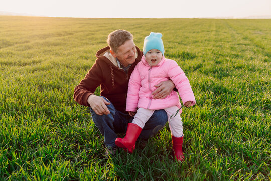 Happy grandfather and granddaughter in the field with sunshine