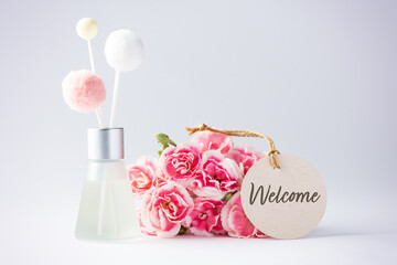 Welcome paper tag with fragrance diffuser and pink flowers
