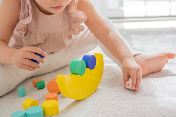 Close up image of a little girl playing with balance blocks on a sustainable wooden toy. Montessori methodology and materials. education, development and learning in the childhood stage - obrazy, fototapety, plakaty
