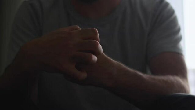 The tense hand movements of a man in a dark room&mdash;praying, scratching, and clenching&mdash;illustrate his battle with mental health issues.