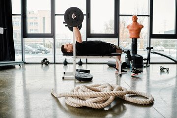 A disabled man with a prosthetic leg lies on a bench, facing a rope in front of him, in a determined workout session. - Powered by Adobe